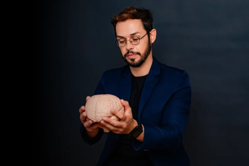 Dr. Allan Felippe, neurocientista, segurando um modelo anatômico do cérebro humano.